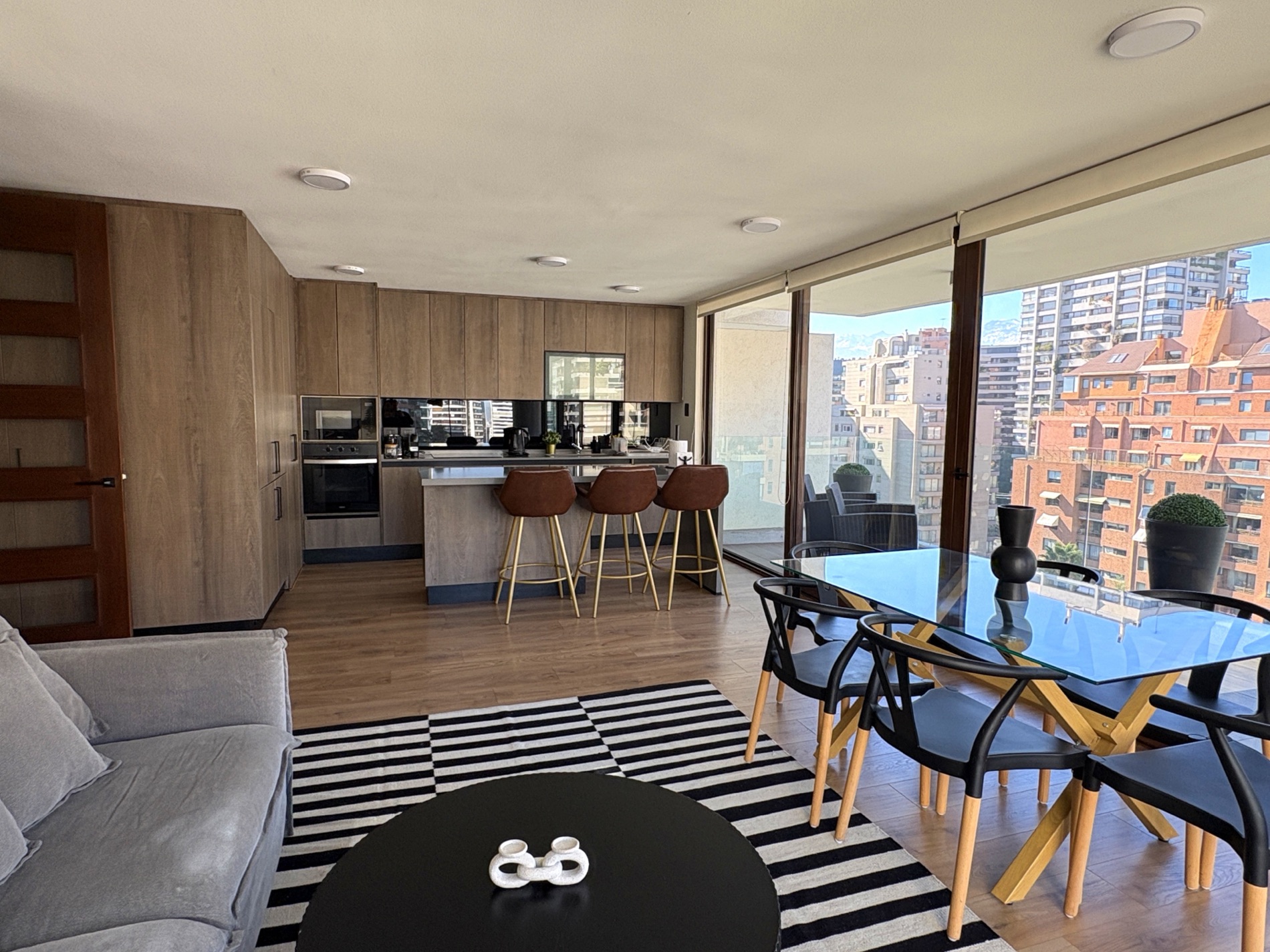 Living comedor de At Home El Golf con ventanales y vista a la ciudad
